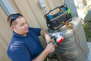 A repairman examines a air conditioning unit.